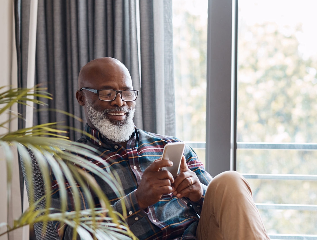 Man on his phone at home sitting on his couch 