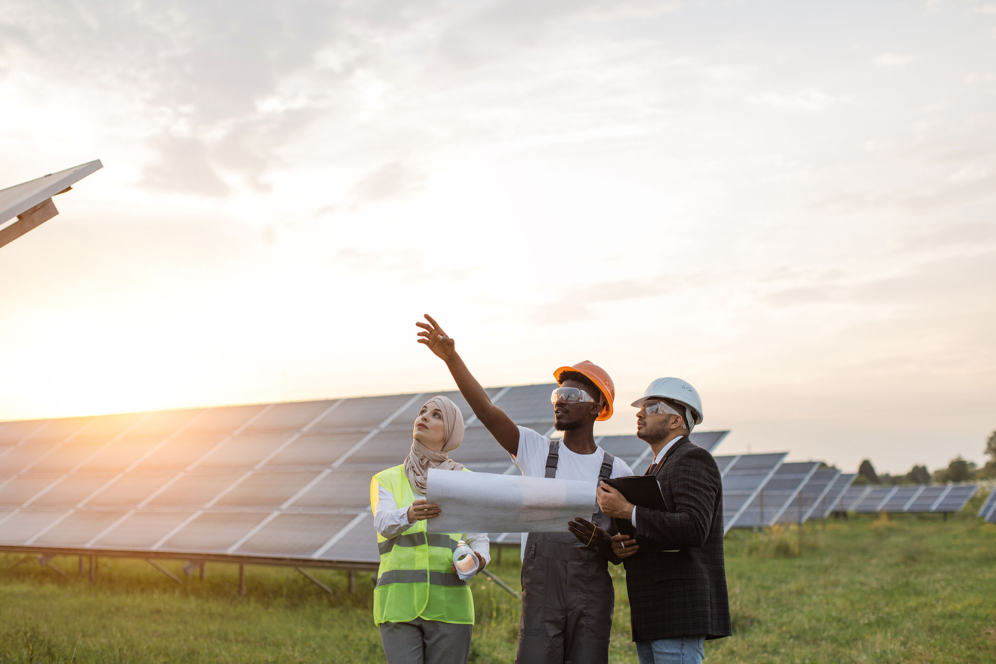 African american technician talking with muslim woman and indian man during working session on solar station. Industrial workers discussing common project of green energy production.