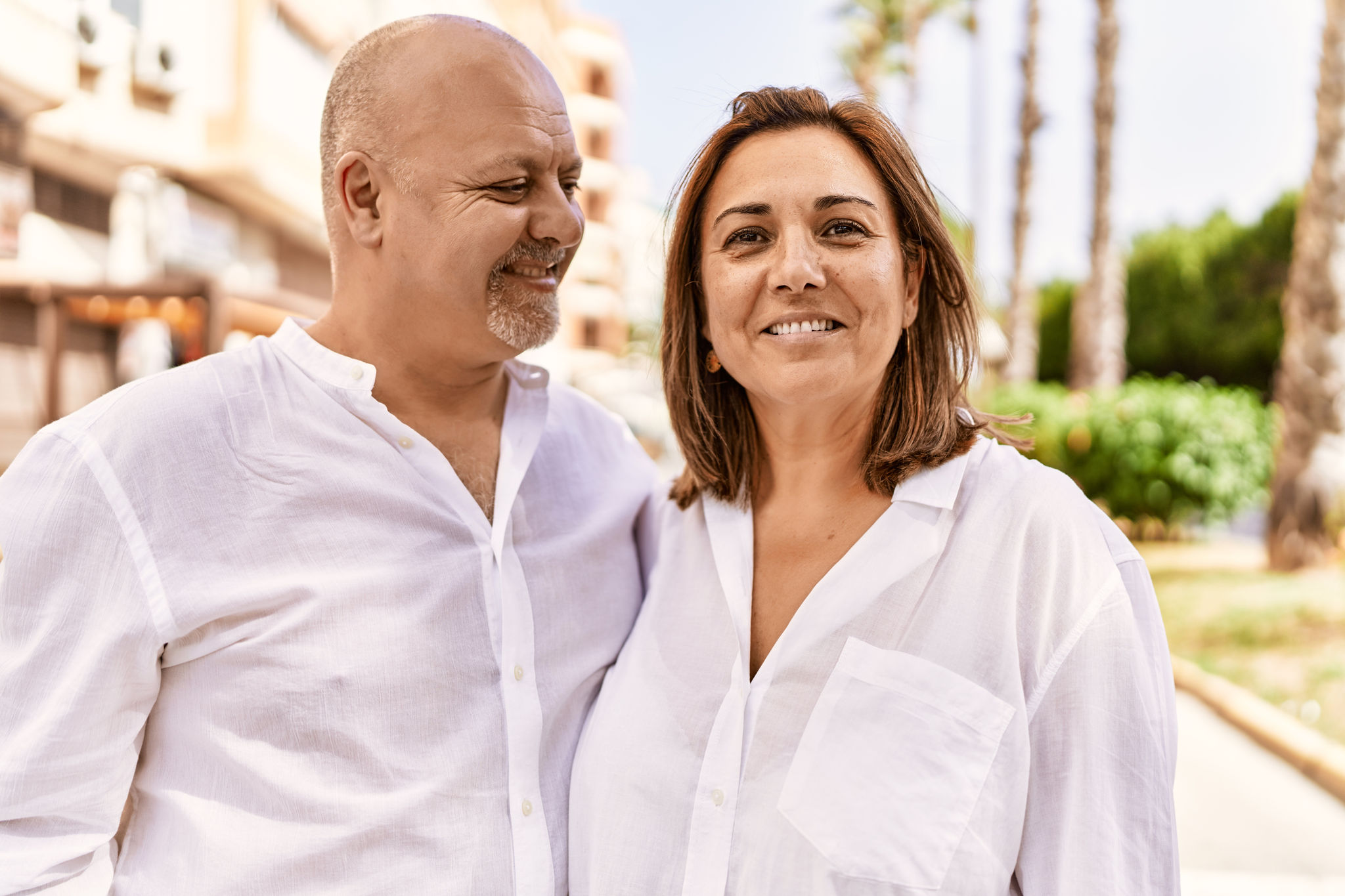 Middle age hispanic couple of husband and wife together on a sunny day outdoors. Smiling happy in love hugging at the city