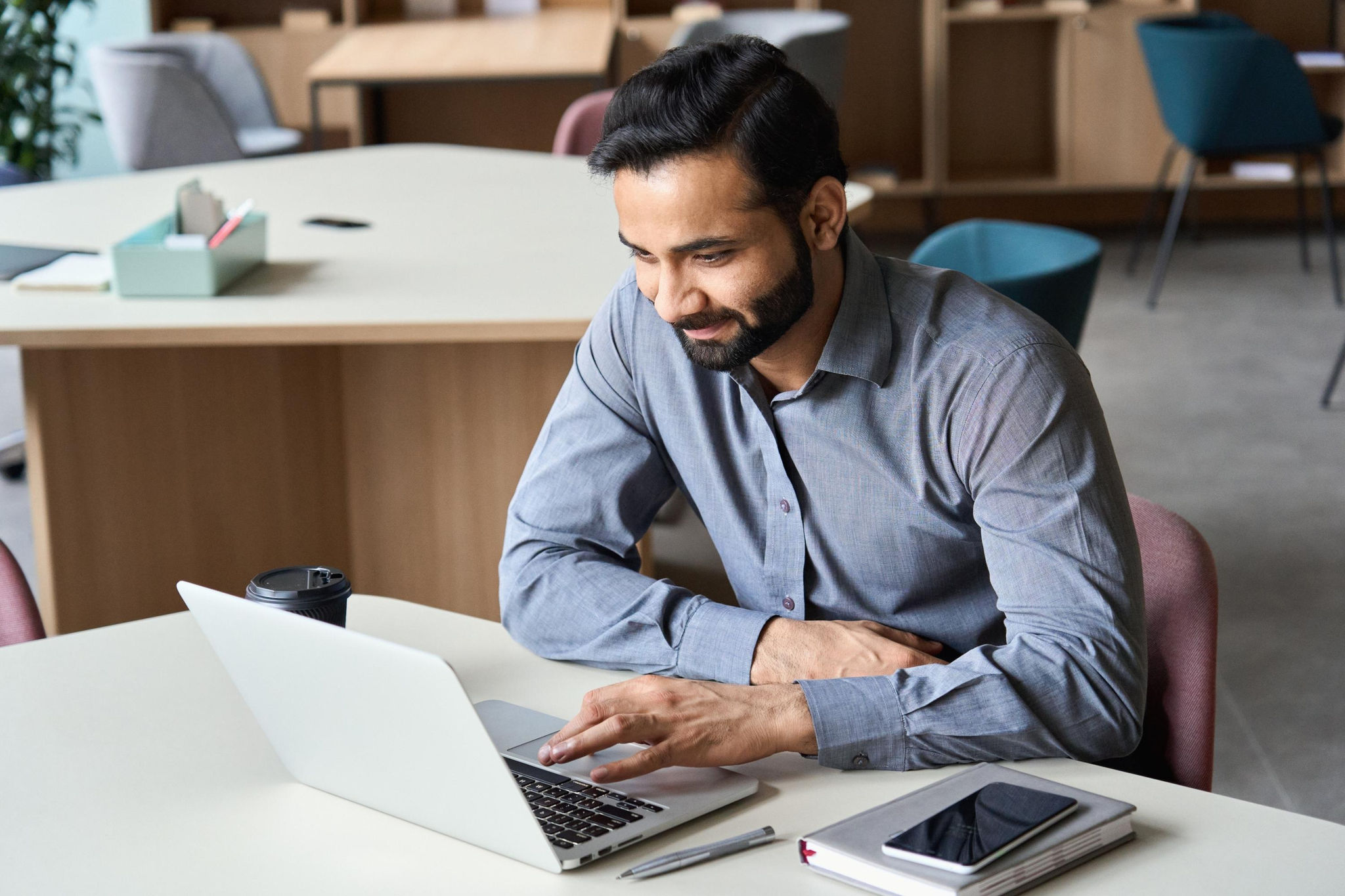 Image of a man working on a laptop in an office space