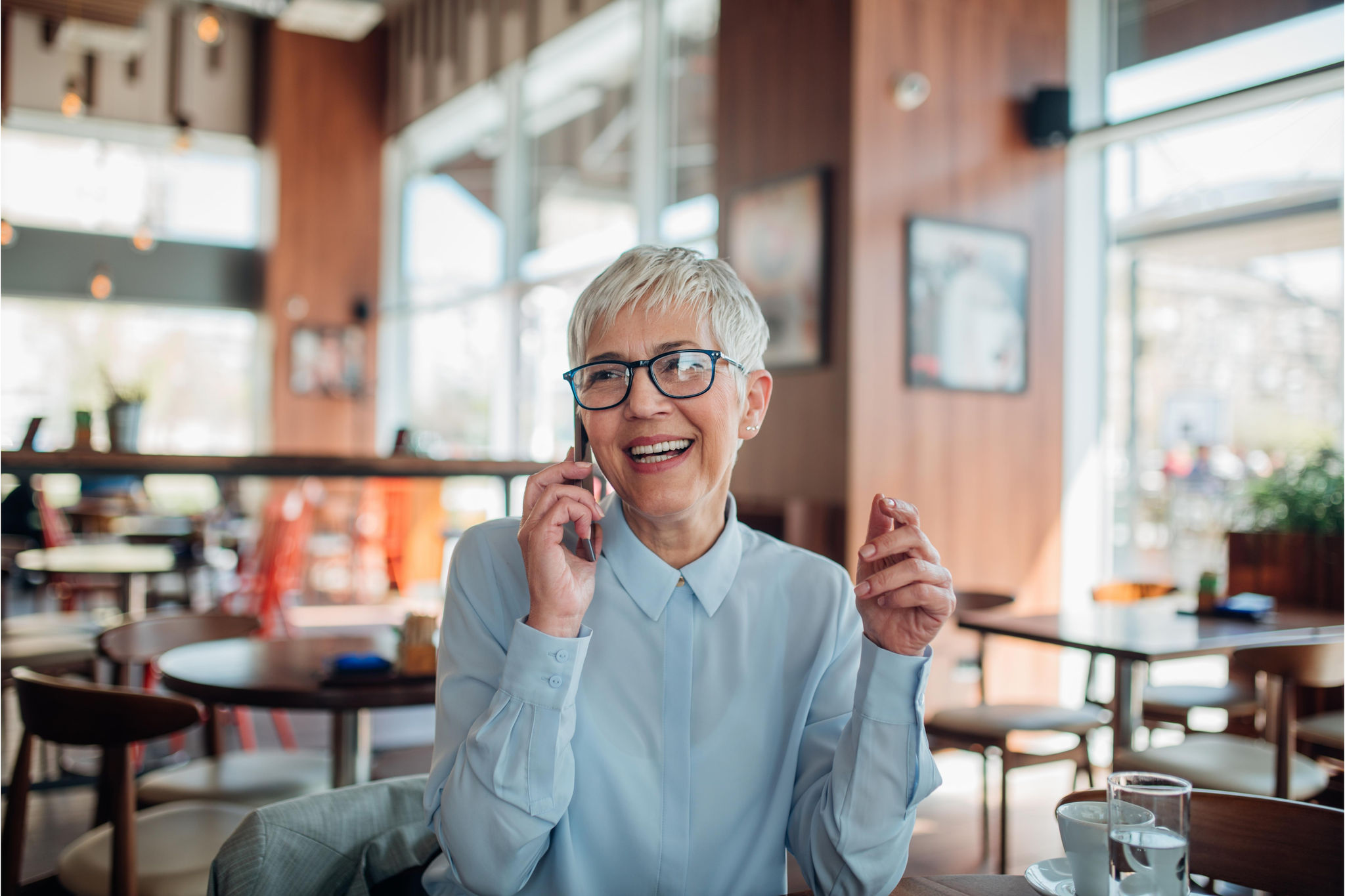 Middle aged woman sitting in cafe talking on phone