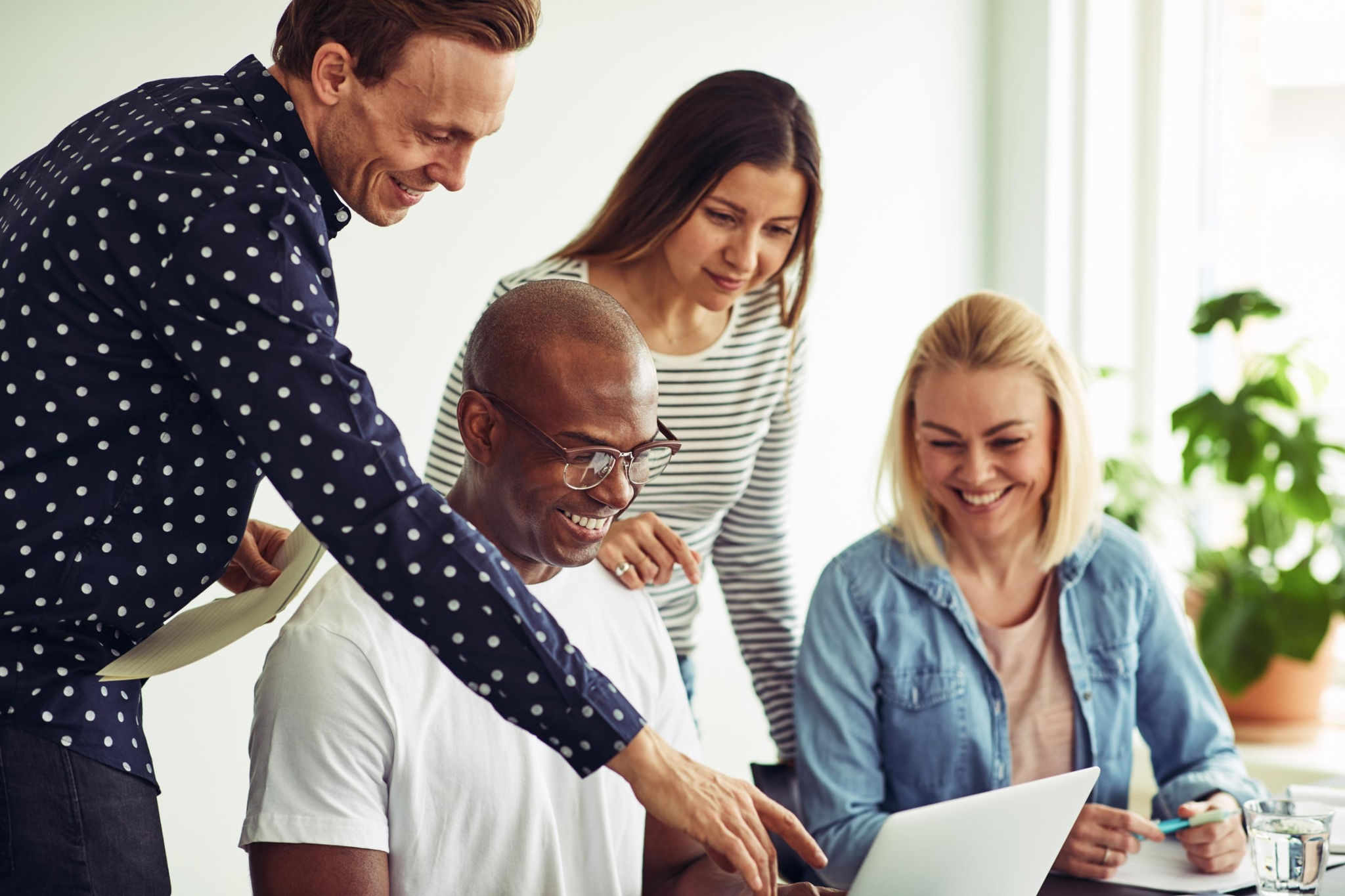 Diverse team of colleagues gathered around a laptop