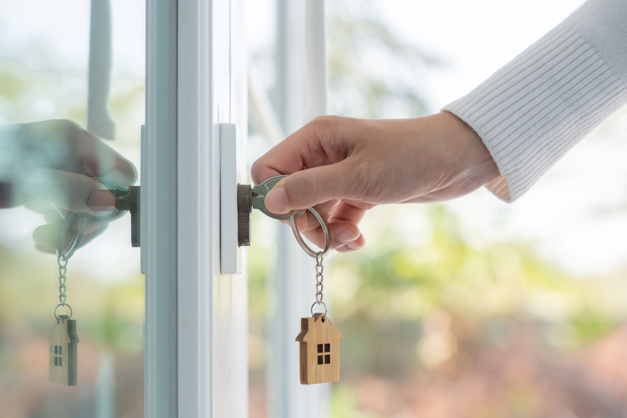 Landlord key for unlocking house is plugged into the door. Second hand house for rent and sale. keychain is blowing in the wind. mortgage for new home, buy, sell, renovate, investment, owner, estate