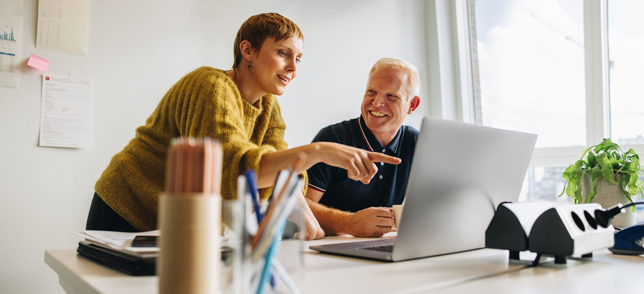 Smiling man and woman in office discussing project. Technology as a part of the work life.