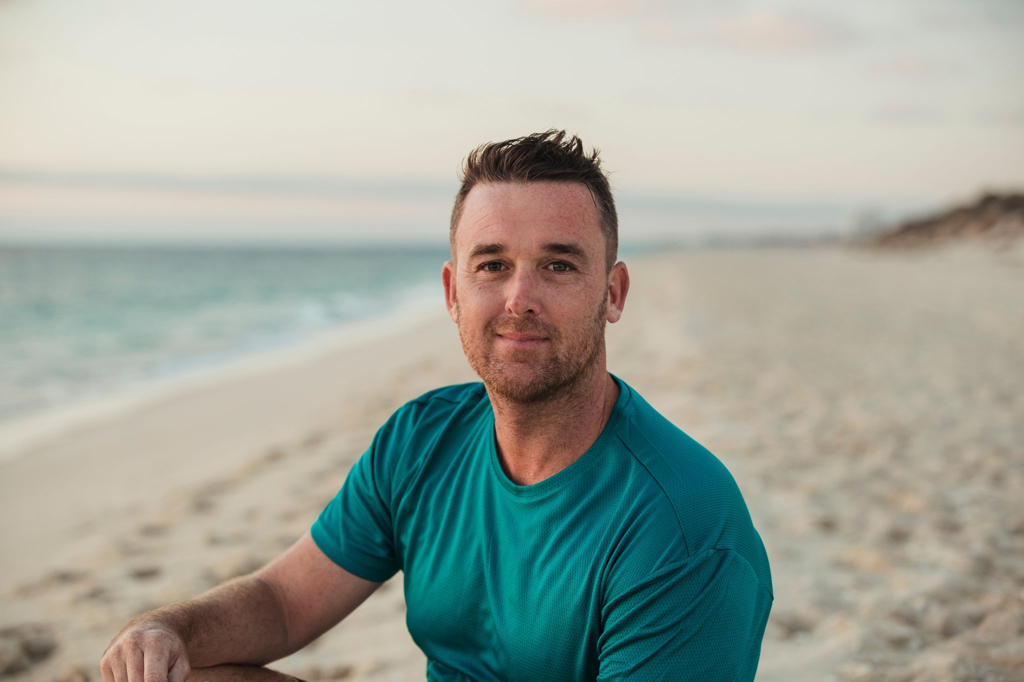 A front view portrait of a mid-adult caucasian man wearing sportswear, he is smiling and looking at the camera.