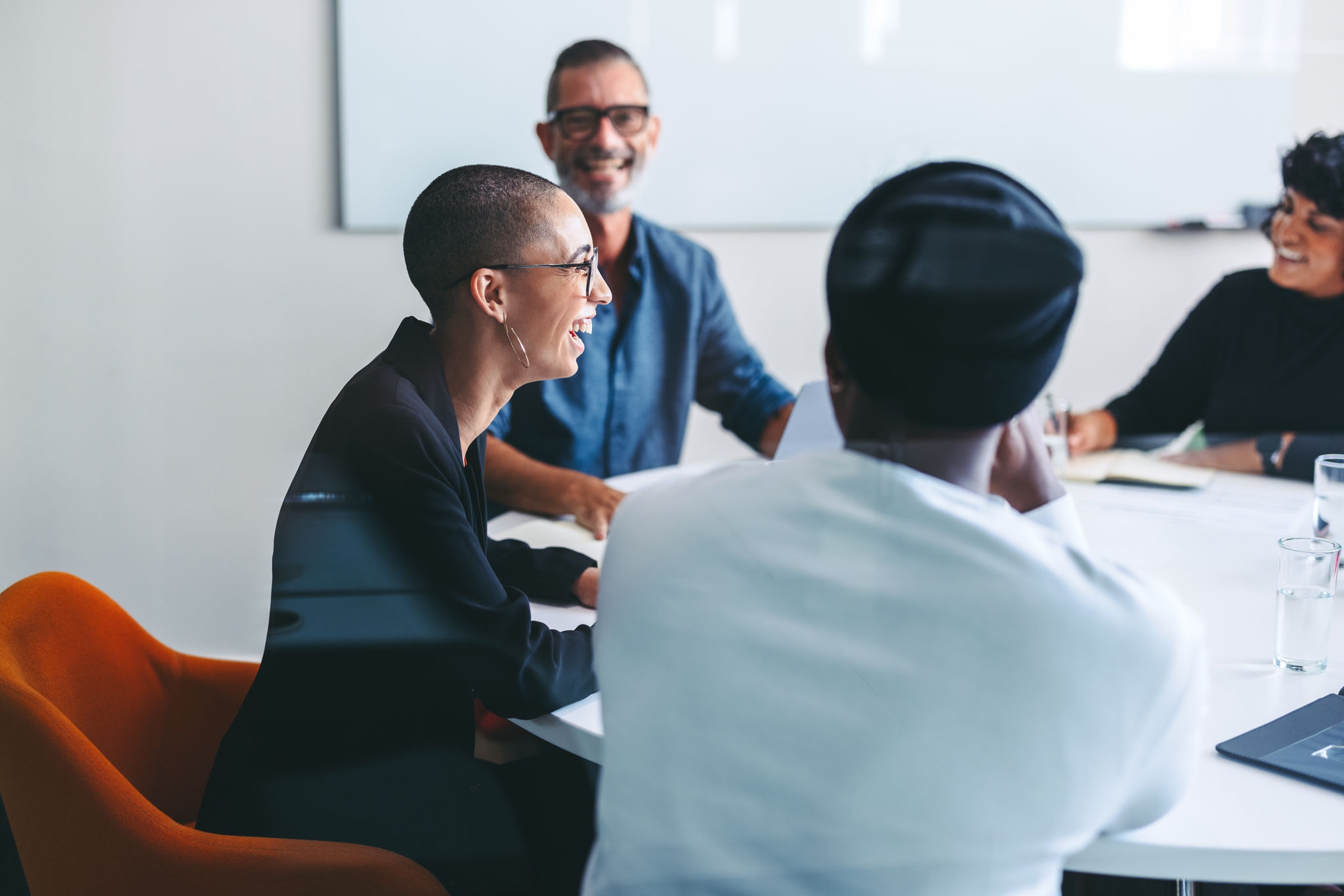 Happy businesspeople smiling cheerfully in a meeting room. Group of successful businesspeople sitting together during their morning briefing in a modern office. Colleagues working together.