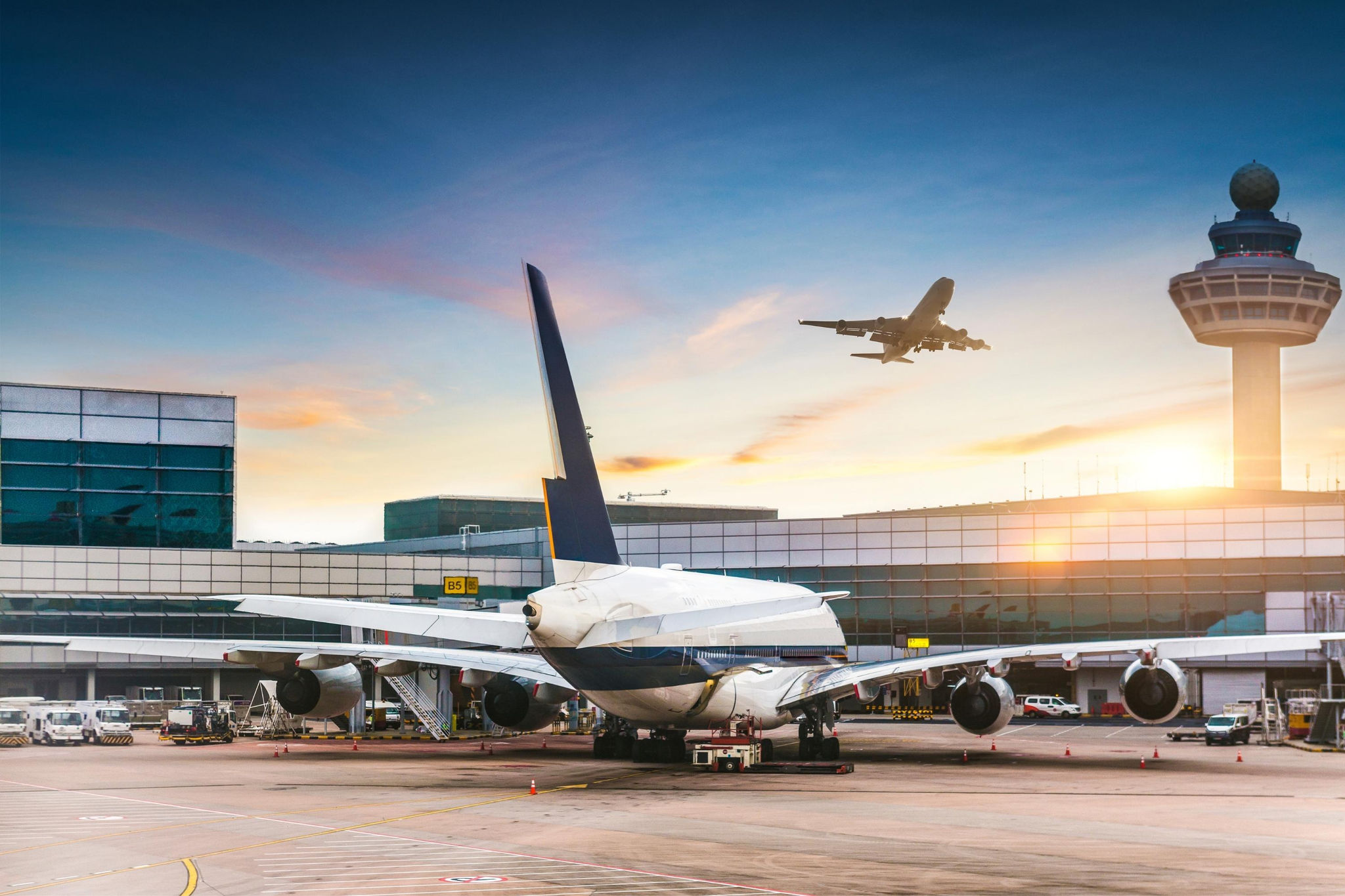 Sunset at a busy international airport with airplane taking off and planes waiting at the gate