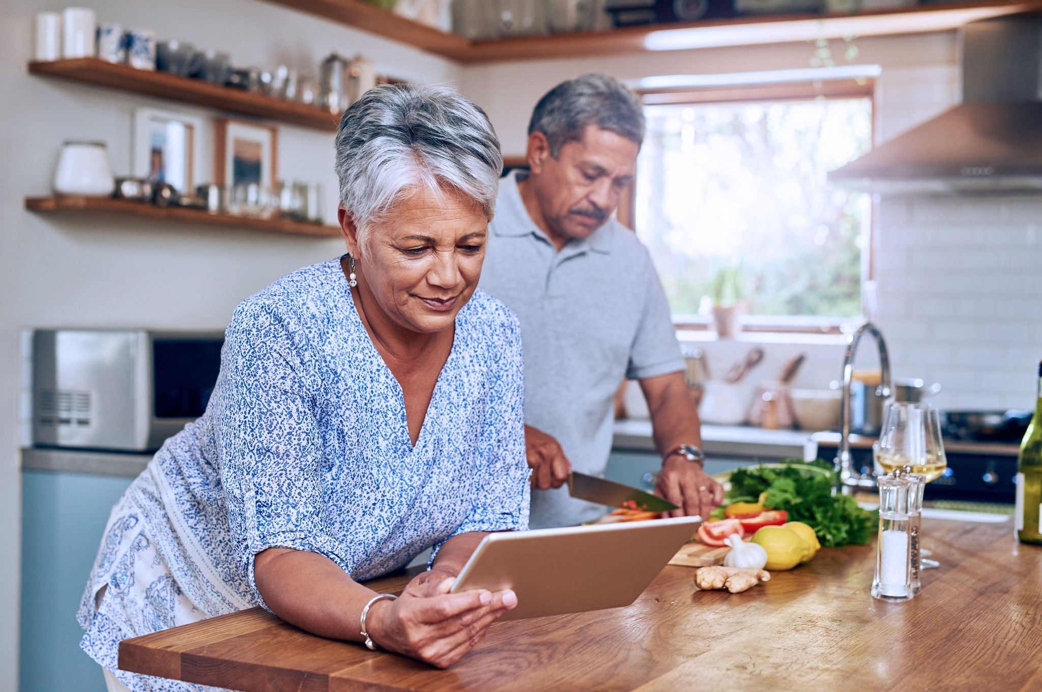 Senior woman at kitchen counter with man, tablet and cooking healthy food together in home. Digital recipe, smile and old couple in house with meal prep, happiness and wellness diet in retirement