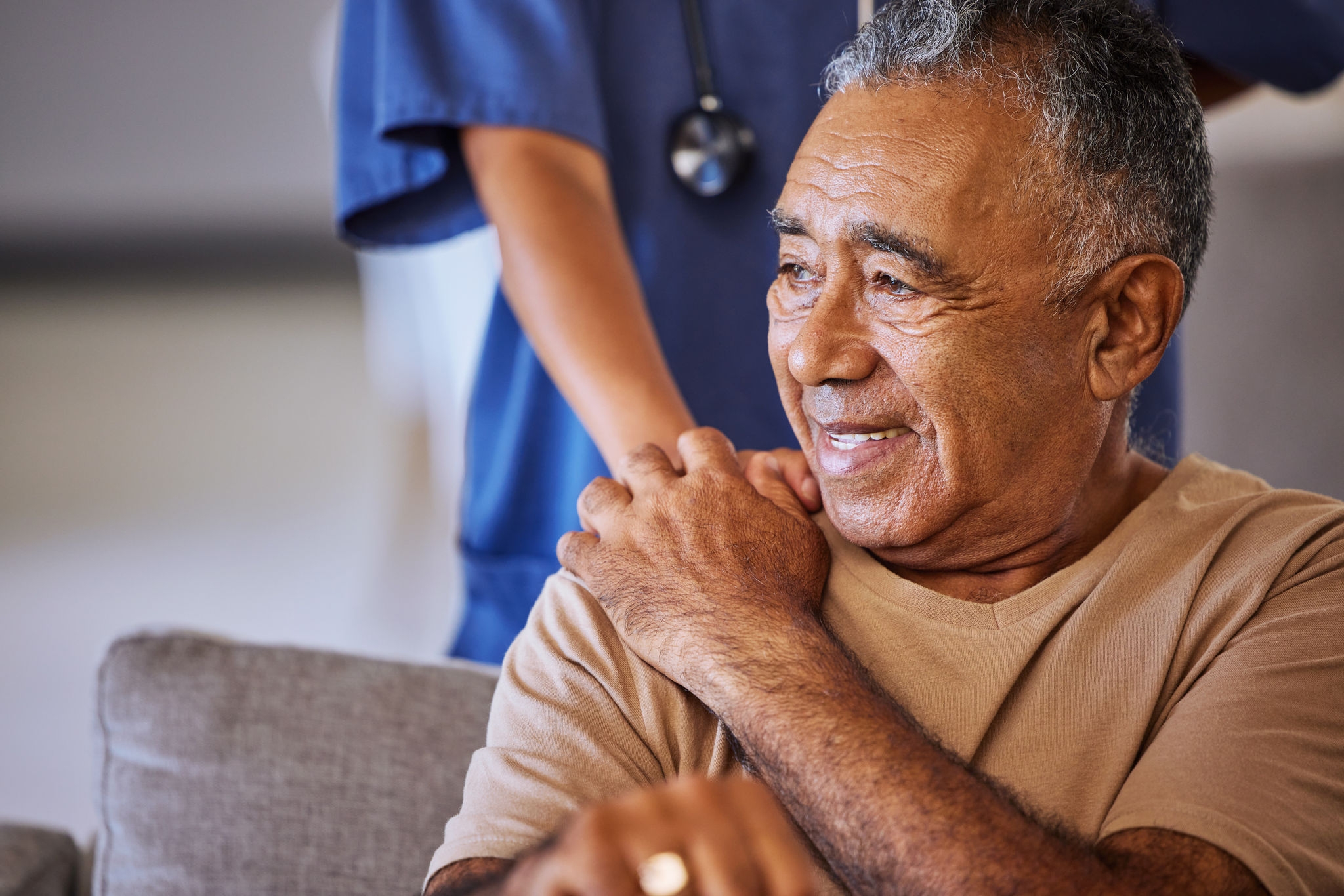 Nurse or doctor give man support during recovery or loss. Caregiver holding hand of her sad senior patient and showing kindness while doing a checkup at a retirement, old age home or hospital.