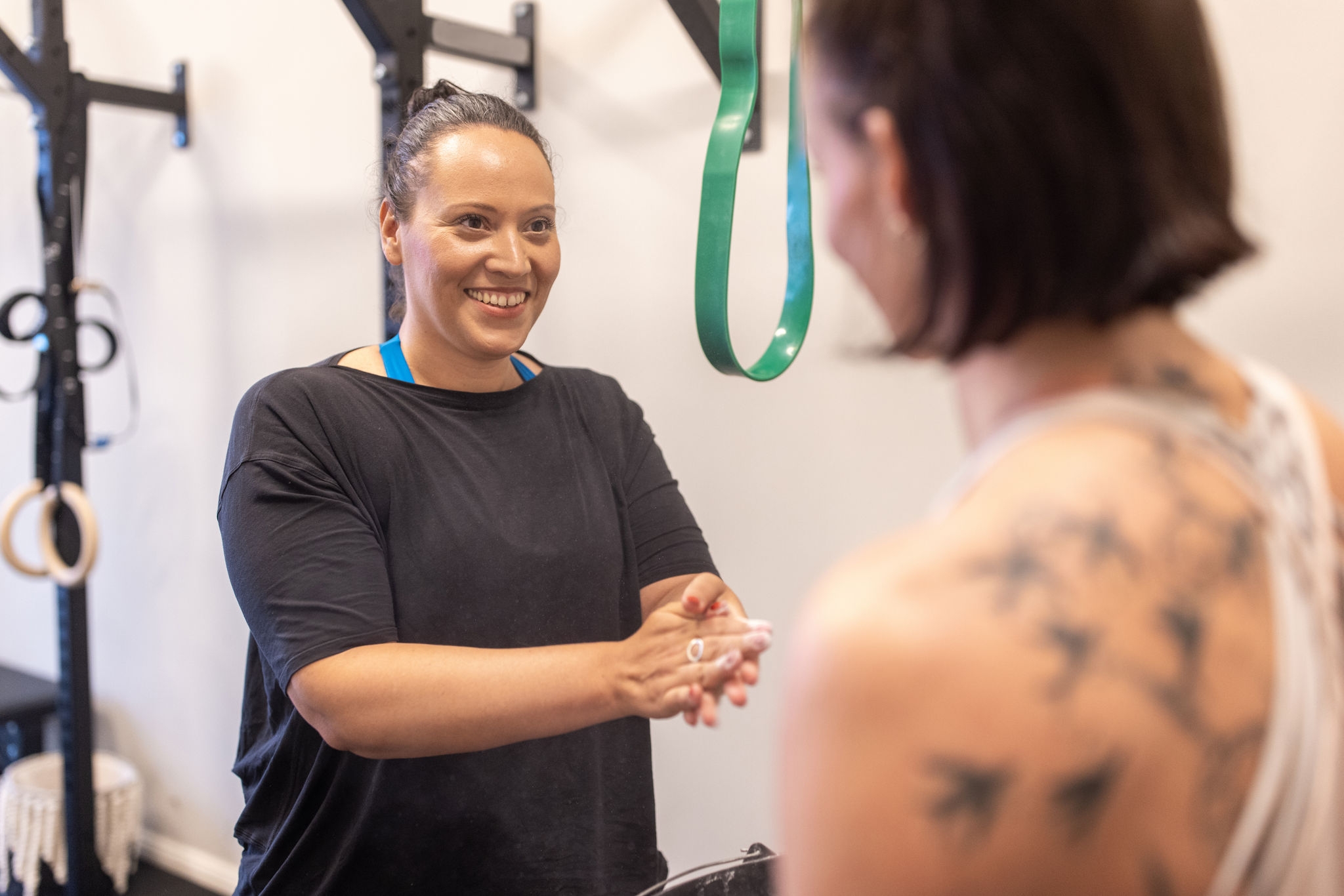 Healthy mid adult woman with her personal trainer in fitness studio. Smiling woman in sportswear talking with her fitness instructor at gym.