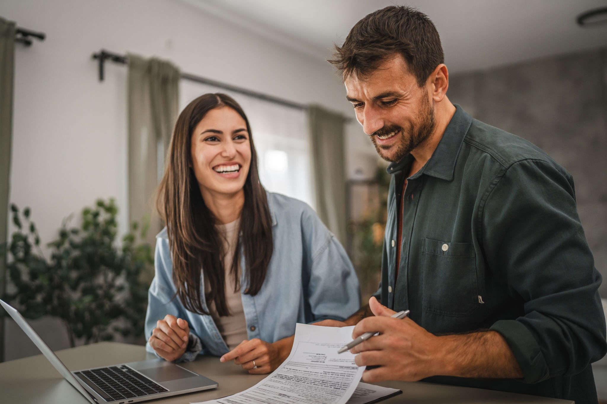 Young couple at home working out their finances on laptop